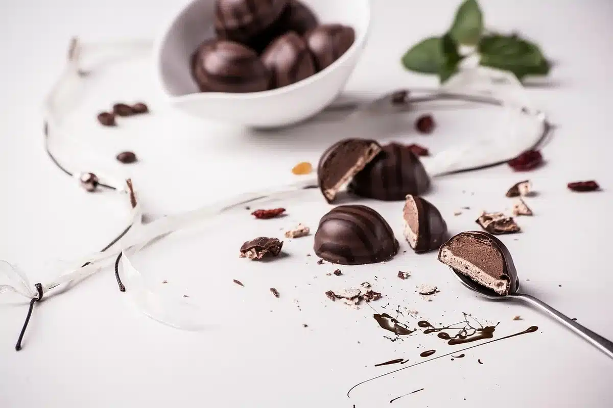 Glossy chocolate ganache in a bowl with a spoon ready to pour over cupcakes