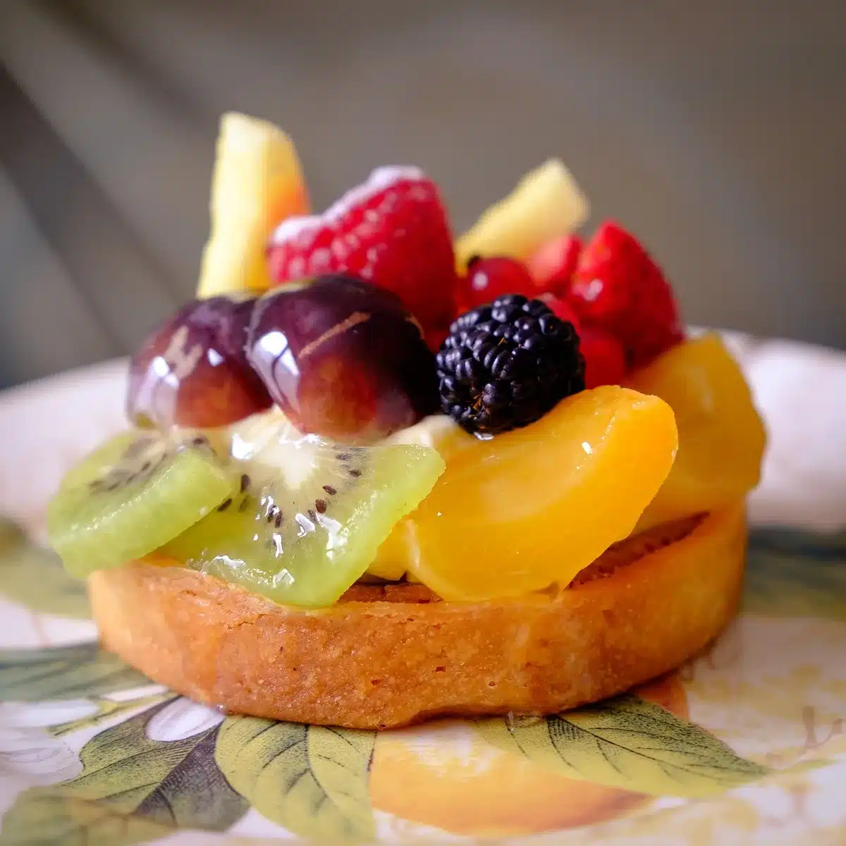 Pouring thin vanilla custard over arranged peaches and blueberries in a pie crust