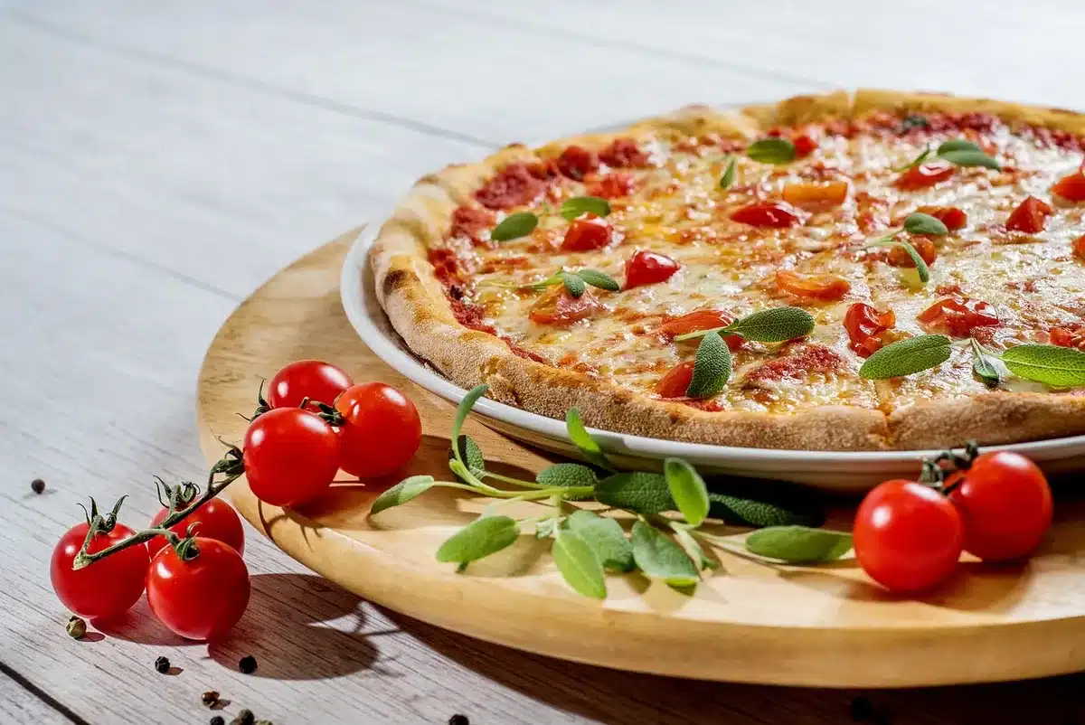 Ingredients laid out for two servings: precooked pinsa, tomatoes, mozzarella and speck