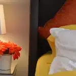 Daylit bedroom with CPAP mask on a bedside table and hands adjusting headstrap