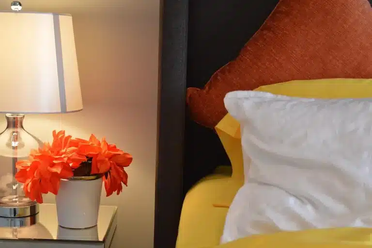 Daylit bedroom with CPAP mask on a bedside table and hands adjusting headstrap