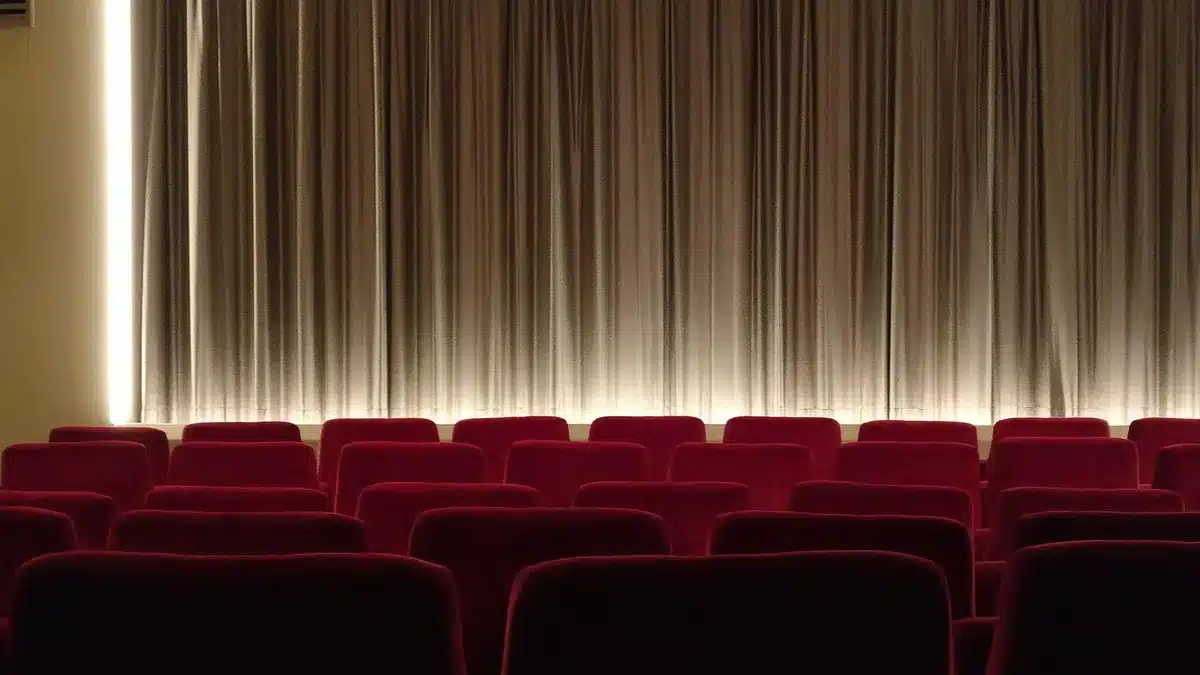 Actor rehearsing onstage with script in hand in a daylight-filled theater
